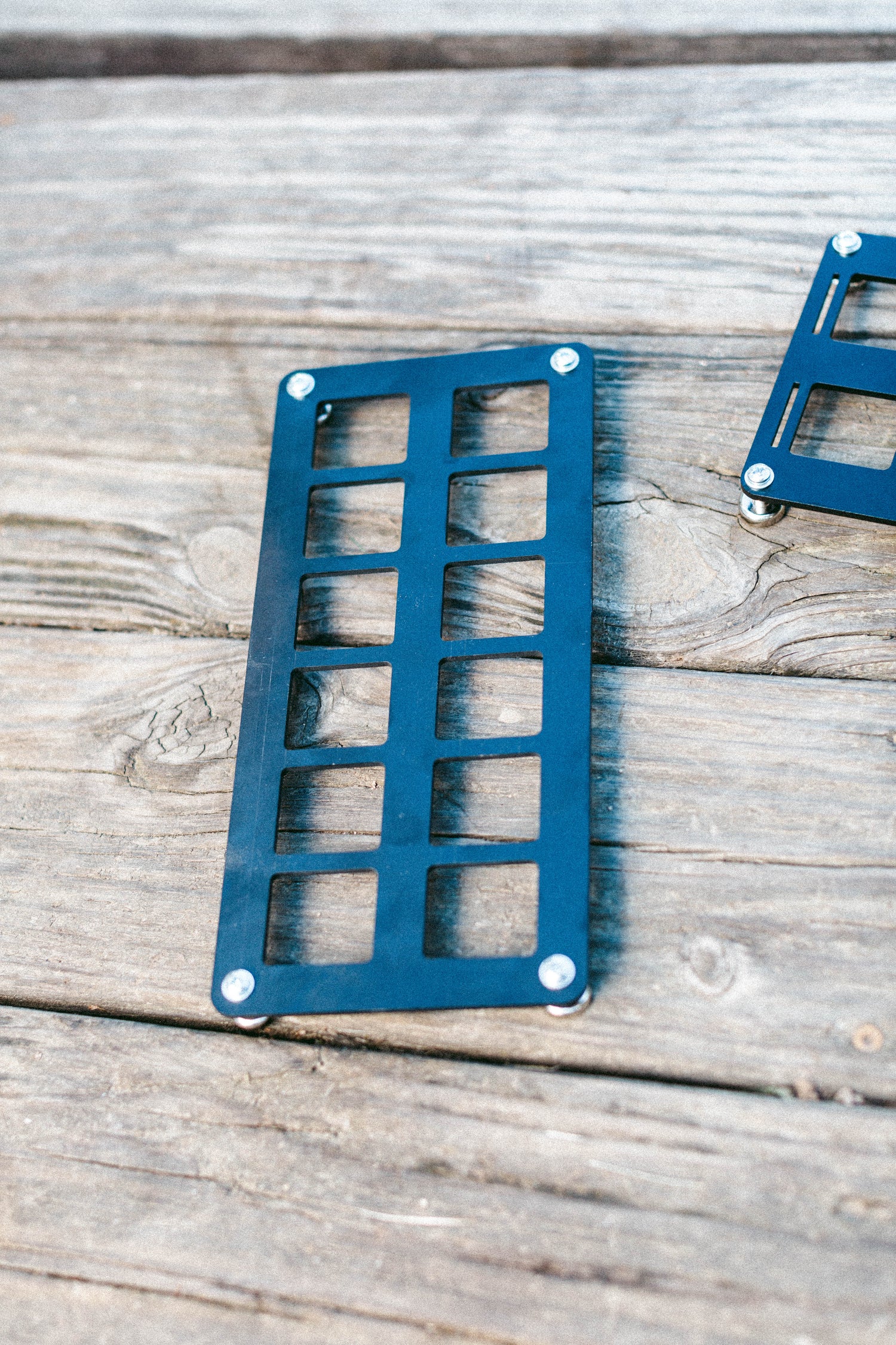 12-slot MOLLE panel made from .125 ABS plastic with corner mounting holes, displayed on a wooden surface.