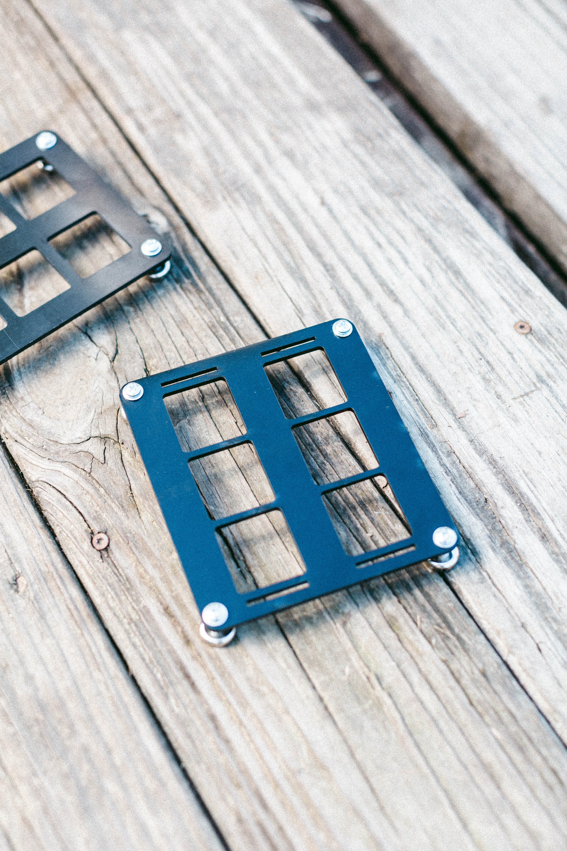 Angled view of the 6-slot ABS MOLLE panel on a wooden surface showing thickness and mounting holes.