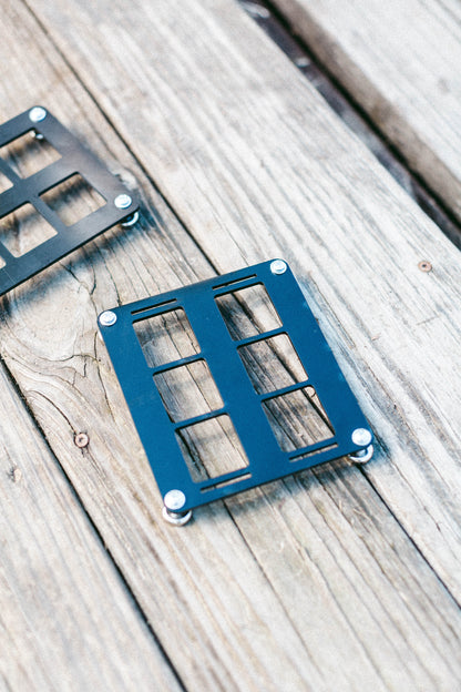 Angled view of the 6-slot ABS MOLLE panel on a wooden surface showing thickness and mounting holes.